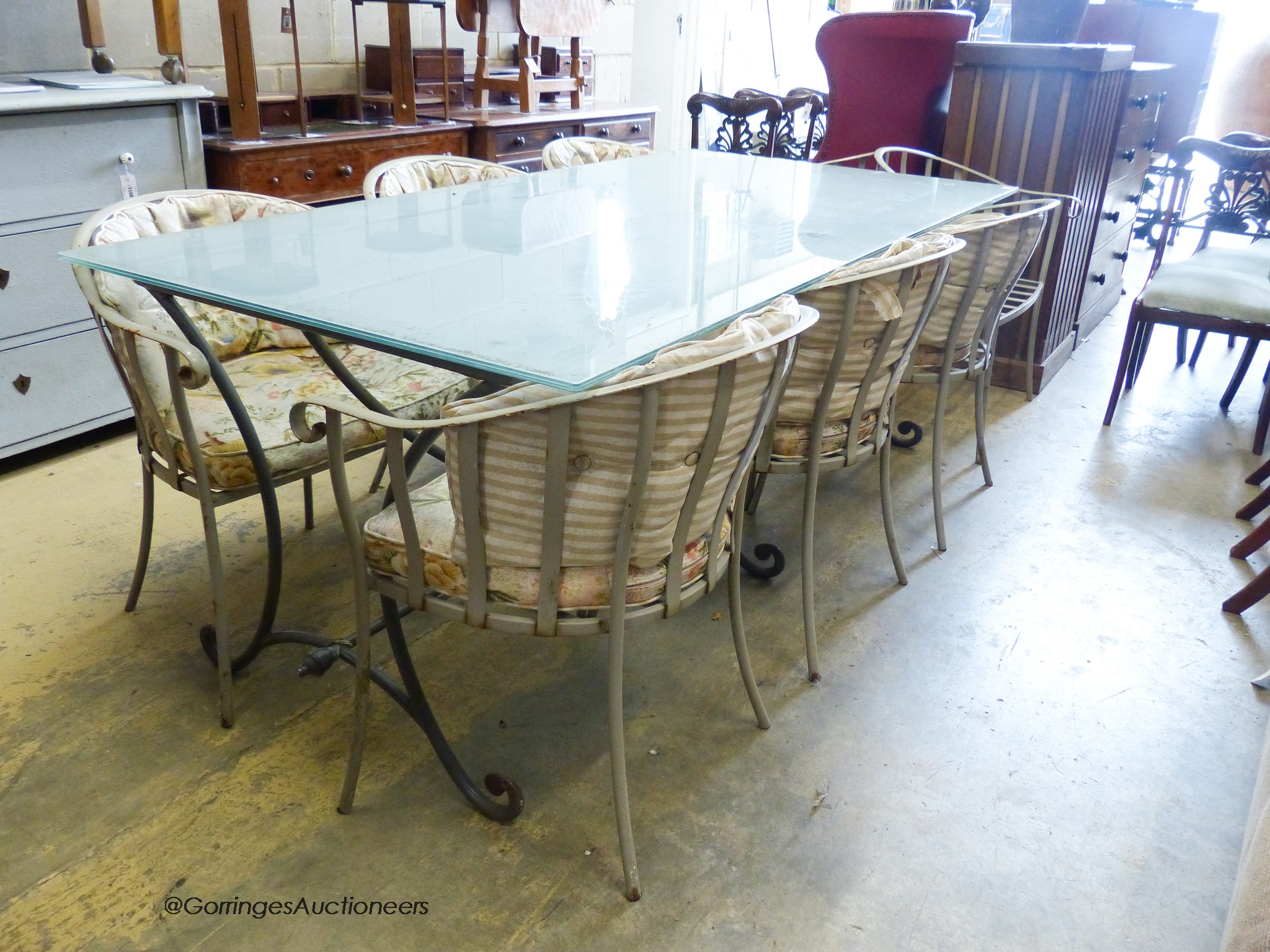 A rectangular glass topped wrought iron garden table and eight chairs. Table, 200x100x75cm.